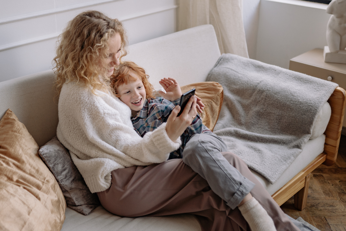A parent and child smiling together on a couch using Chorsies